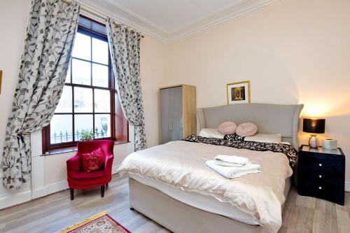 阿伯丁Inviting 9-Bed House in Aberdeen的一间卧室配有一张大床和一张红色椅子