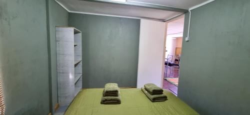 瓜达尔港Cabaña el Sauco的一间设有绿床的房间,里面摆放着两把椅子
