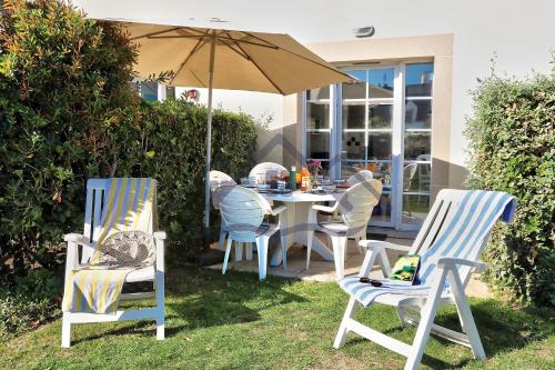 吉尔维内克LocaLise - Maison E2 au Guilvinec - A 20m de la mer avec jardin et piscine - Tout à pied, plage, port, centre commerces, marché - Wifi inclus - Vue mer de la chambre - Animaux bienvenus - Linge de lit inclus的院子里的桌椅和遮阳伞