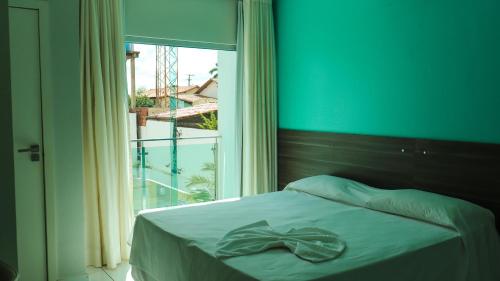 AcailandiaGênova Palace Hotel的窗户间里一张带弓的床铺