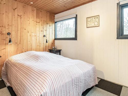 RoslevHoliday home Roslev IX的卧室配有一张床铺,位于带木墙的房间内