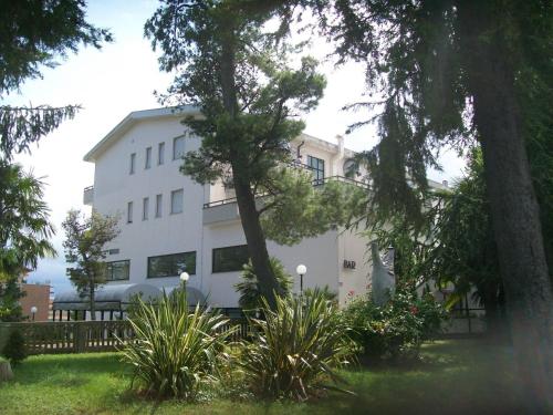 阿特里杜帕克酒店的一座白色的建筑,前面有树木和植物