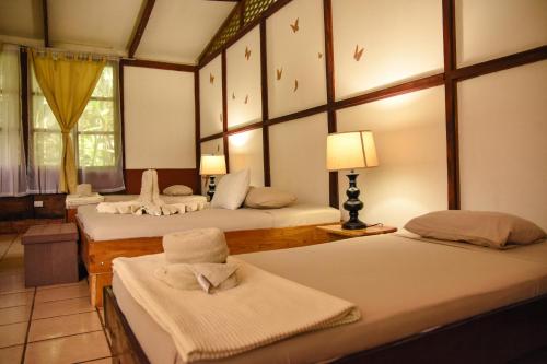 Puerto ViejoChilamate Rainforest Eco Retreat的带三张床和一盏灯的房间