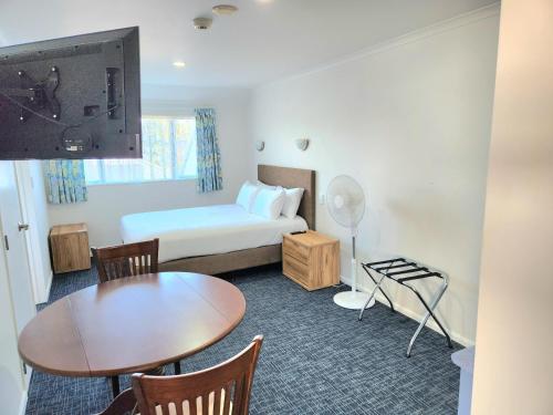 奥克兰Botany Palms Motel的小酒店客房设有床、桌子和桌子。