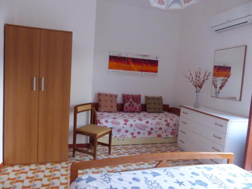 圣维托罗卡波Villetta Fiorita的一间卧室配有一张床、一个橱柜和一把椅子