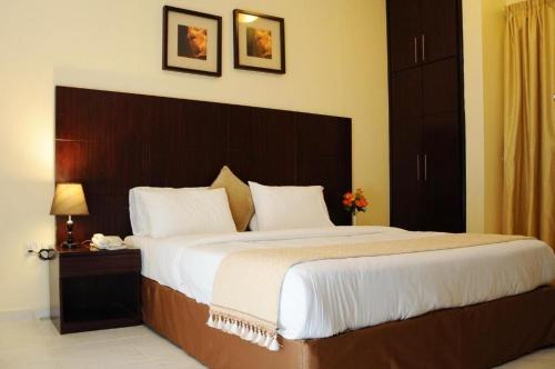 阿吉曼New Royal Palace Hotel Apartments的一间卧室配有一张大床和木制床头板