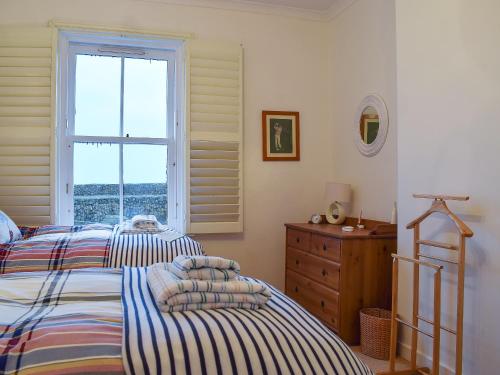 塞拉戴克Nautilus Cottage的卧室设有两张床,配有窗户和梳妆台。
