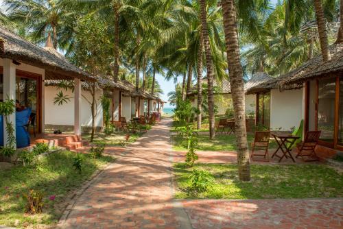 美奈阿南达度假村酒店的海滩上一排种有棕榈树的小屋
