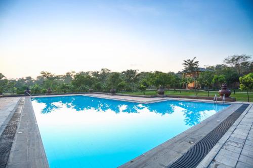 锡吉里亚Kaveri Resort Sigiriya的一个蓝色的海水和树木背景的游泳池