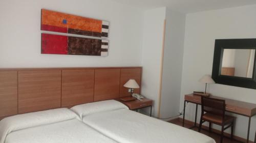 隆达莫里诺酒店的一间卧室配有一张床、一张书桌和一面镜子