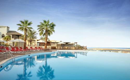 拉斯阿尔卡麦Peaceful Private Villa at Five Star Beach Resort的一个带椅子和棕榈树的大型游泳池