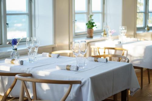 Bådsted斯塔莫巴德酒店的用餐室配有带玻璃杯和椅子的白色桌子