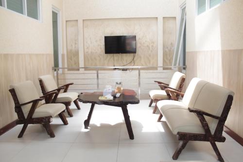 万隆G10 Guest House Near Asia Afrika Bandung的一间带椅子和桌子的房间以及一台电视