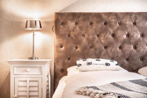 文尼斯塔特Aparthotel Friesenhof的一间卧室配有软垫床头板和一张带灯的床
