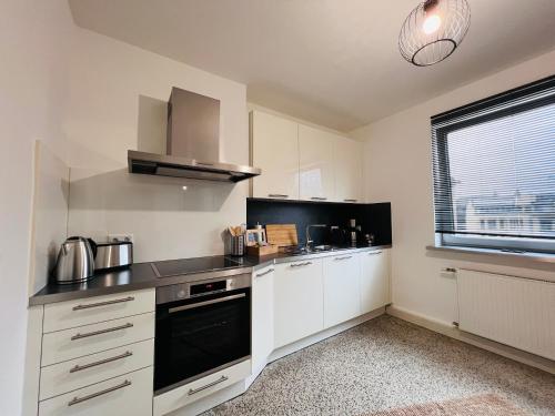 科布伦茨BIG-6-Guests-Kingsize-Netflix-Badewanne-Hauptbahnhof-Zentral的厨房配有白色橱柜和黑炉灶烤箱。