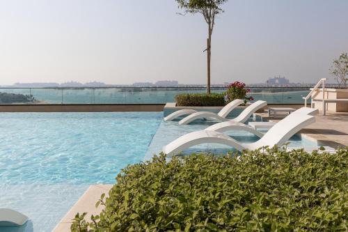 迪拜Sea View with Private Beach Access! 3BR & Maid Rm的一个带两把白色椅子的游泳池