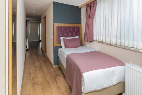 伊斯坦布尔黑珍珠酒店的一间卧室配有一张大床和紫色床头板