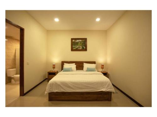 丹戎Dawn Light Villa, Sire的一间卧室配有一张带2个床头柜和镜子的床
