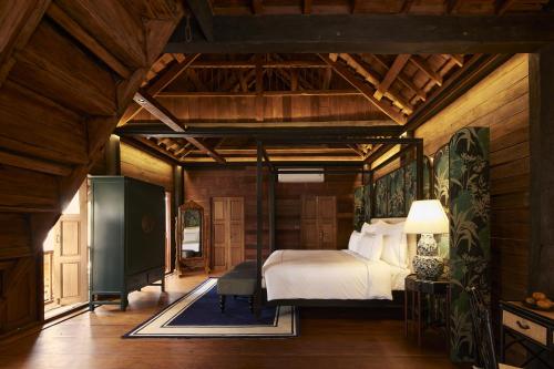 清迈Aleenta Retreat Chiang Mai的卧室配有一张床铺,位于带木墙的房间内
