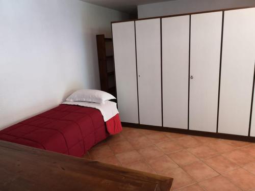 彼得拉桑塔Garden's House的卧室配有白色橱柜和红色床。