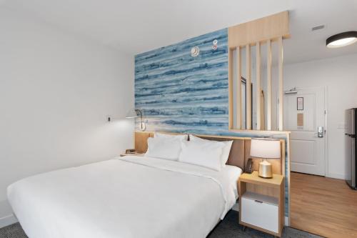 White HallTownePlace Suites by Marriott White Hall的卧室配有白色的床,墙上挂有蓝色的画作