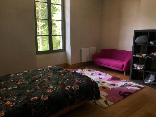 SaissacLe Lodge Saissac的一间卧室配有一张床和一张粉红色的沙发