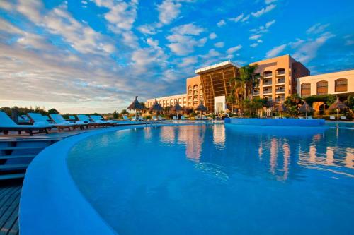 科洛尼亚-德尔萨克拉门托Sheraton Colonia Golf & Spa Resort的度假村的游泳池,设有蓝色椅子和建筑