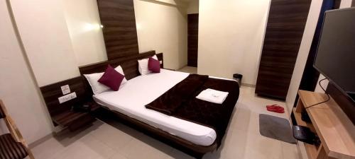 瓦皮Hotel Orange的一间卧室配有一张带紫色枕头的床和一台电视。