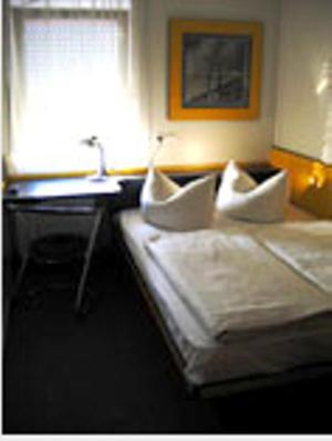 代特尔巴赫佩利坎汽车旅馆的配有一张床、一张书桌和一扇窗户的酒店客房