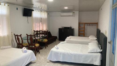 约帕尔Hotel El Broche的客房设有三张床、椅子和电视。