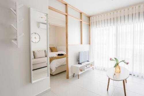 沃洛斯ESTEA Quality Living的一间白色的小房间,配有床和镜子