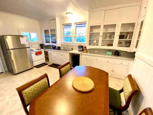 希洛YOUR HILO HOMEBASE - Lovely 3 Bedroom in Heart of Hilo with AC!的厨房配有木桌和冰箱。