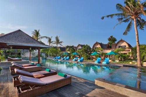 吉利特拉旺安欧巴克别墅饭店的度假村的游泳池,设有躺椅和棕榈树