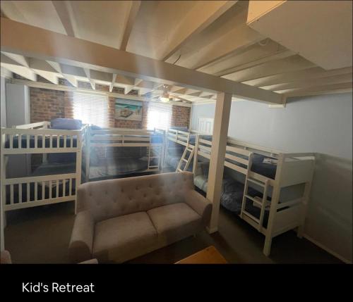 麦夸里港5 OClock Somewhere 6BR sleeps 18 with Kids Retreat的客房设有两张双层床和一张沙发。