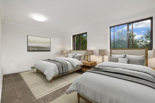 金德拜恩Alps Lakeview Lodge的白色客房的两张床,设有窗户