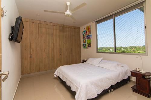 蒙特里亚Apartamento acogedor的一间卧室设有一张床、一台电视和一个窗口。