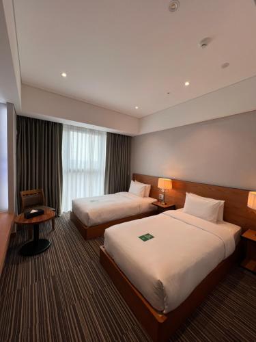仁川市Hotel Tour Incheon Airport Hotel & Suites的酒店客房设有两张床和窗户。
