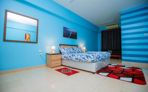 达累斯萨拉姆Queens Rentals - Studio Apartments - Village Walkway - Masaki - Dar es Salaam的一间拥有蓝色墙壁的卧室、一张床和一个梳妆台