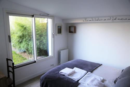 南特Chambre d'Hôtes Les Petits Oiseaux的一间卧室配有床,窗户配有毛巾