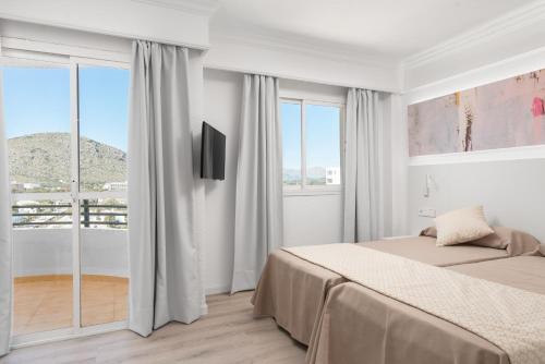 阿尔库迪亚港Alcudia Beach Apartments的白色的卧室设有床和窗户