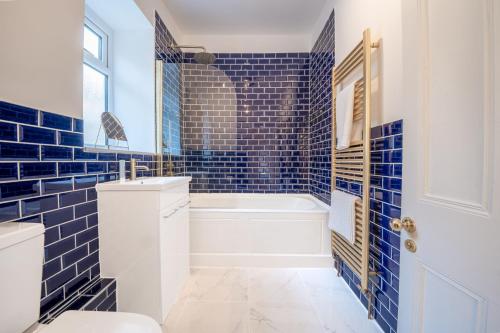 马特洛克Corner Cottage的蓝色瓷砖浴室设有浴缸和卫生间