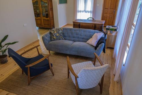 Kefar Pinesהבקתה על השדות的客厅配有蓝色的沙发和两把椅子