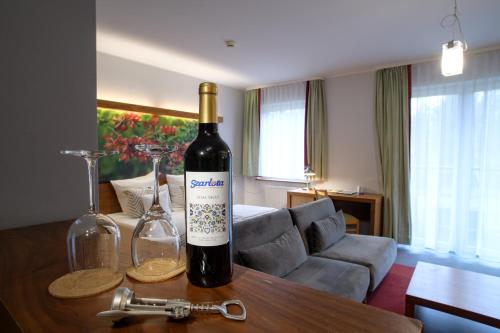 科希切日纳Hotel Szarlota - Kompleksowo na Kaszubach的桌子上放有一瓶葡萄酒和两杯酒