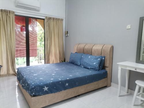 马六甲EBH INN的一间卧室配有一张带蓝色床单的床和一扇窗户。