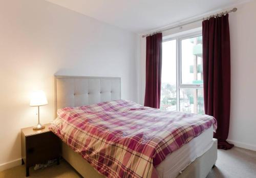 伦敦2-Bed Apartment only 15 mins from Central London的一间卧室配有一张带铺着地毯的床和窗户。