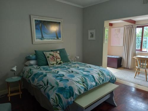 开普敦Sunshine Cottage的一间卧室配有一张床、一张桌子和一个窗户。