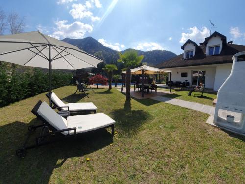 格拉韦洛纳托切Villa Mariel Lago Maggiore luxury Suite & Wellness的庭院设有两把躺椅和一把遮阳伞