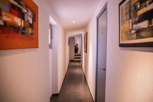 拉加尔德Auberge Sainte Marguerite的走廊设有白色墙壁、瓷砖地板和绘画作品