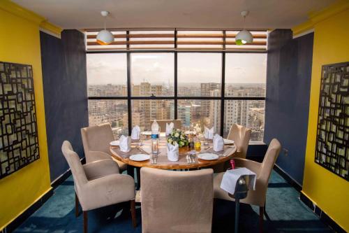达累斯萨拉姆达累斯萨拉姆金郁金香市中心酒店的一间带桌椅和大窗户的用餐室