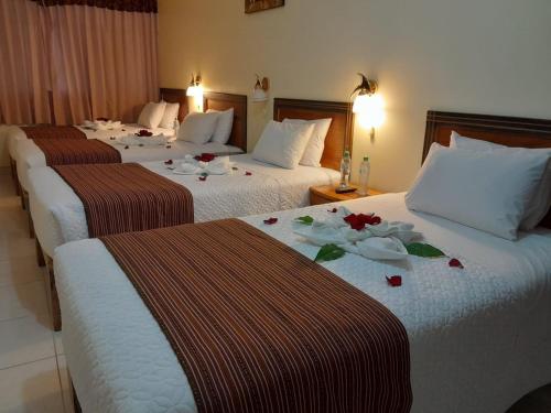 马丘比丘Margarita's House Machupicchu的酒店内有3张床,上面有鲜花